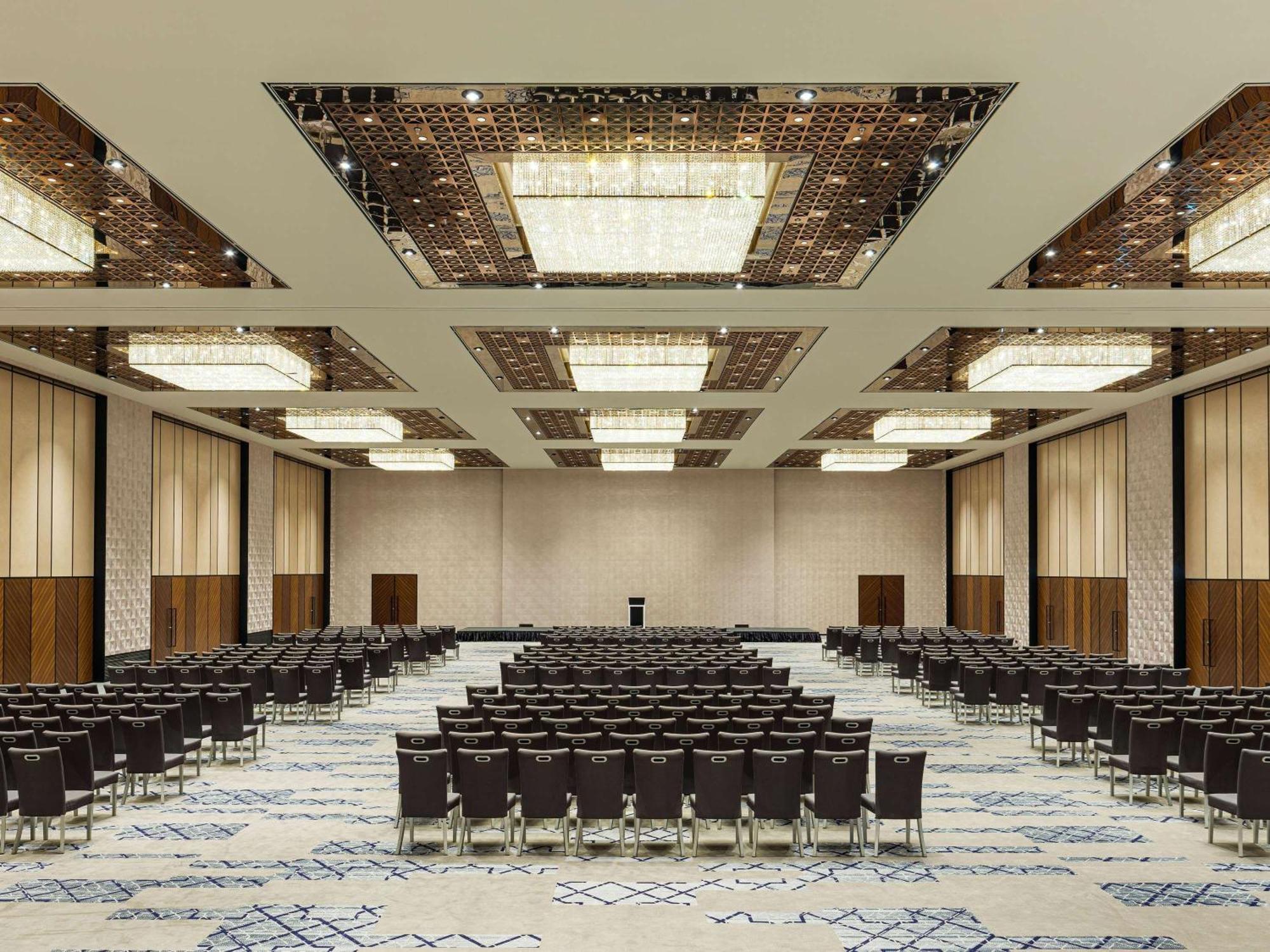 Swissotel The Bosphorus Istanbul Exterior photo The photo shows a large conference or event room equipped with a spacious layout. It features numerous rows of dark chairs arranged facing a central area, likely intended for a speaker or presentation. The ceiling has elegant lighting fixtures and a 