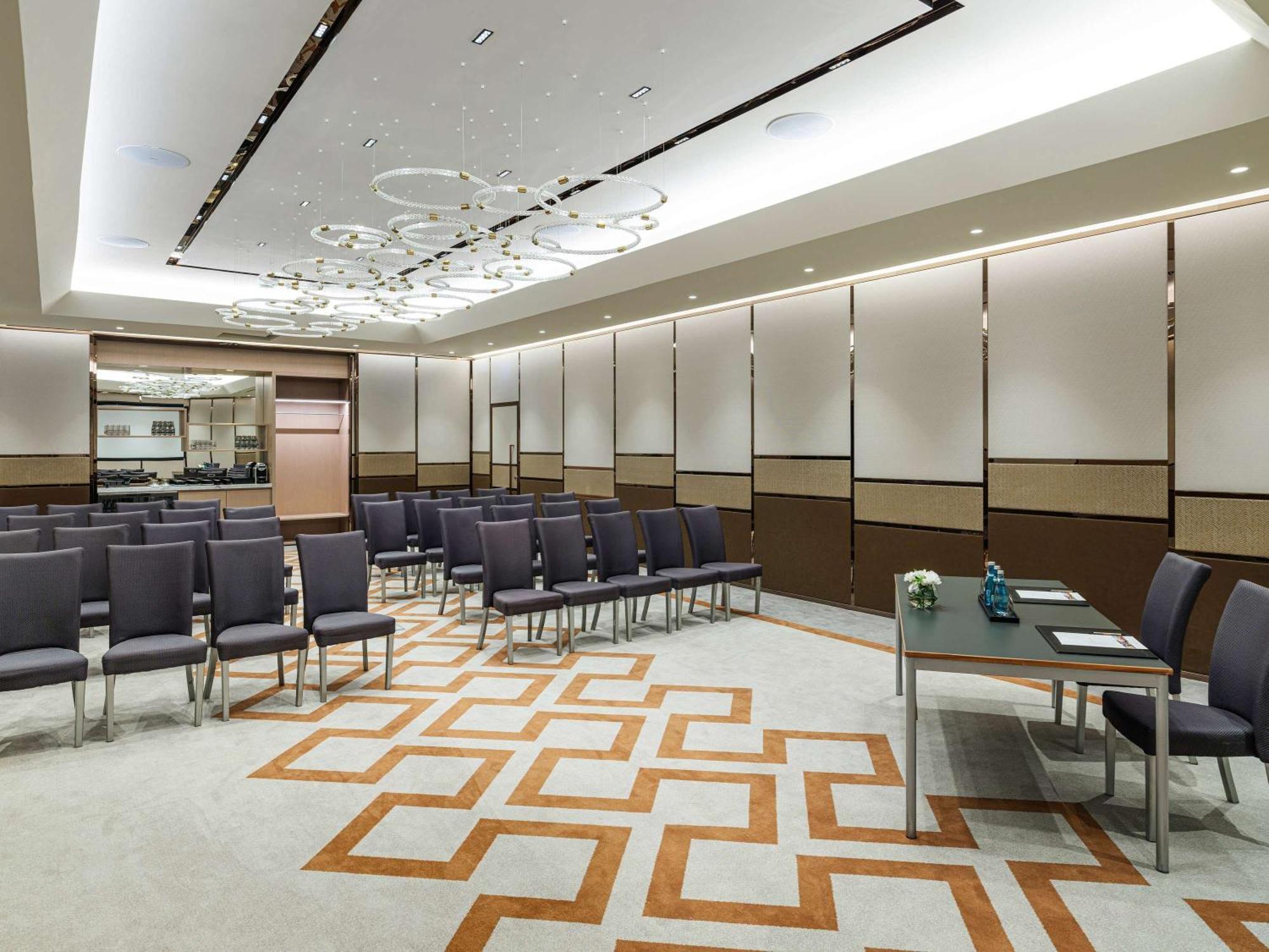 Swissotel The Bosphorus Istanbul Exterior photo The photo shows a modern conference or meeting room. It features rows of gray chairs arranged in a neat pattern, suggesting preparation for an event or presentation. The floor has a decorative geometric carpet design in light and dark colors. The roo