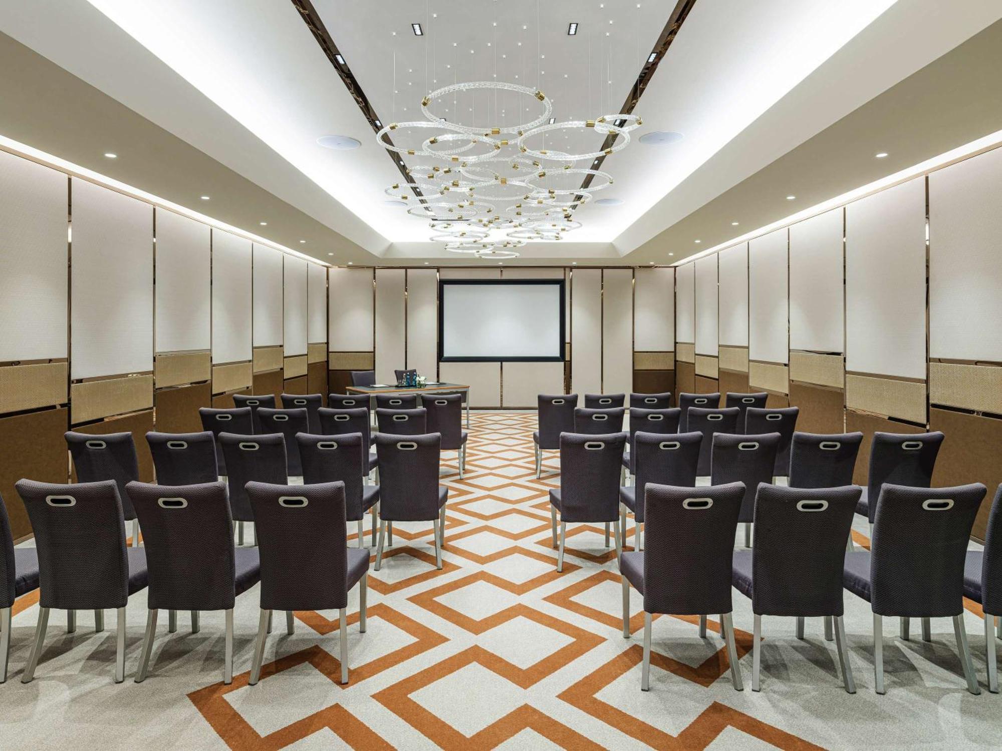 Swissotel The Bosphorus Istanbul Exterior photo The photo shows an interior of a conference room. It features a well-organized seating arrangement with black chairs facing a front presentation area, which includes a screen. The room has a modern design with elegant lighting elements on the ceiling