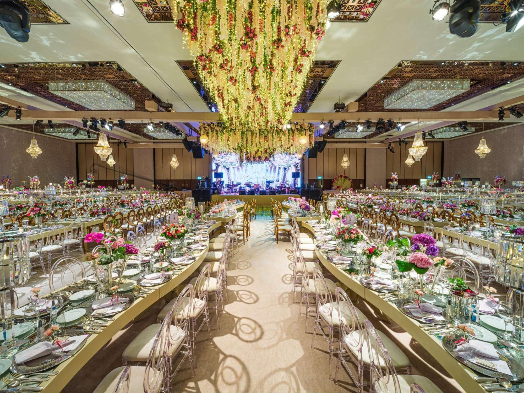 Swissotel The Bosphorus Istanbul Exterior photo The photo shows an elegantly decorated banquet hall set up for an event. There are long tables arranged in a U-shape, adorned with floral centerpieces and neatly set dinnerware. The decor features vibrant flowers in various colors. Above the tables, 