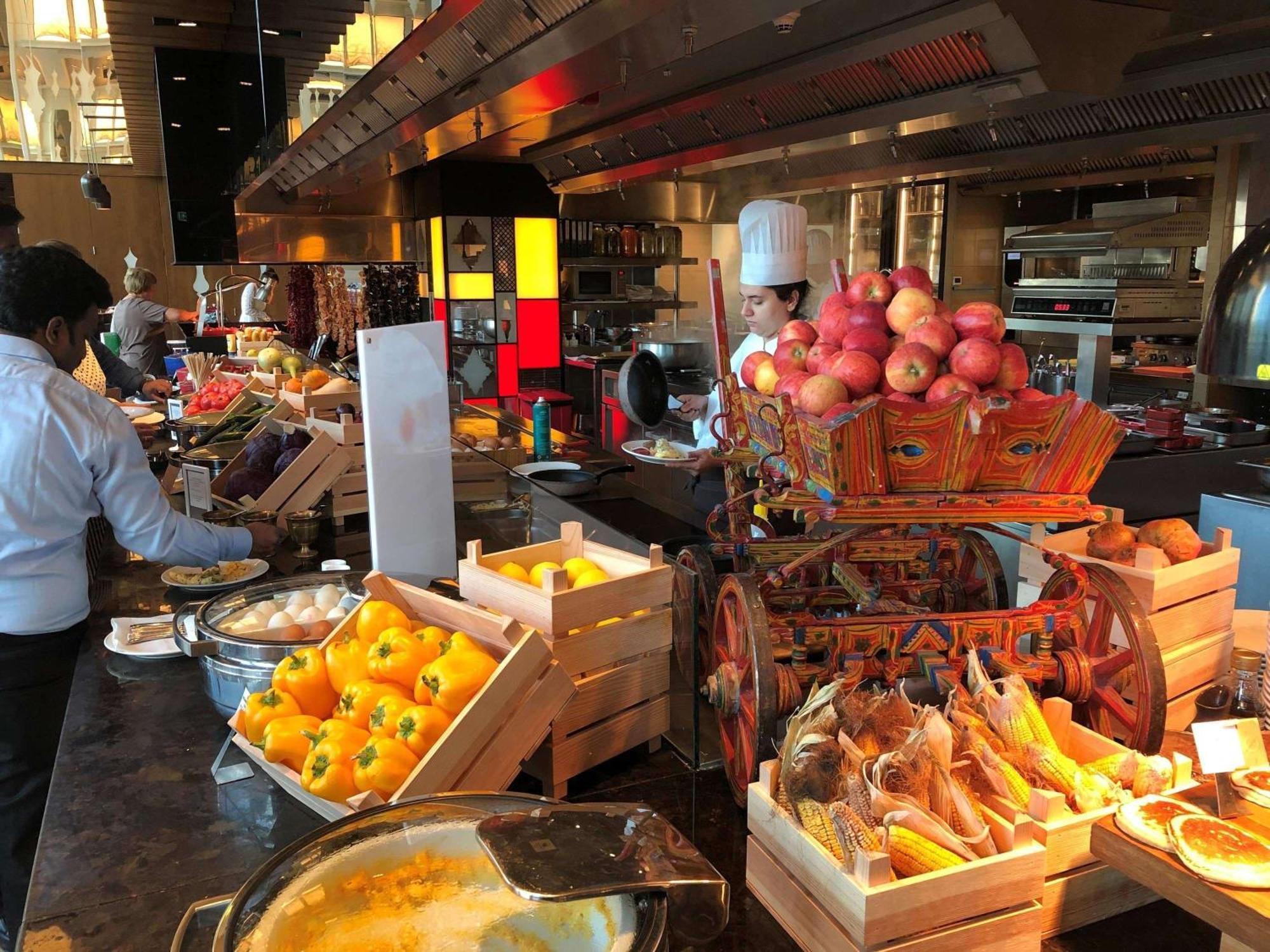 Swissotel The Bosphorus Istanbul Exterior photo The photo shows a vibrant buffet setup in a restaurant. There are various displays of fresh fruits and vegetables, including apples and pumpkins, arranged in wooden crates. In the foreground, one can see a pot or a bowl of food, possibly a warm dish.