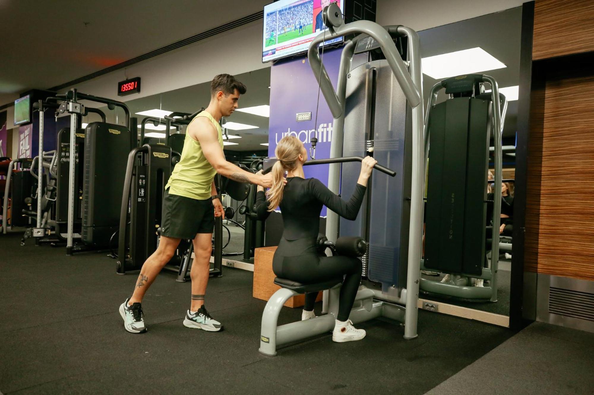 Swissotel The Bosphorus Istanbul Exterior photo The photo shows a gym scene where a man is assisting a woman with her workout. The woman is seated on a weight machine, performing a rowing exercise, while the man stands beside her, likely providing support or guidance. In the background, there is a